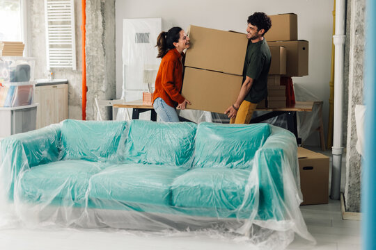 Happy couple carrying boxes into new apartment, moving day - Powered by Adobe