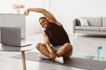 Workout. Happy Sporty Black Guy Doing Stretching At Laptop Exercising Sitting On Floor At Home....