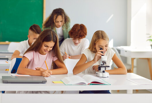 Classroom school study, happy pupils working with microscope discover world of science, experiment. Young students and female teacher learning biology in class, enjoy scientific interesting lesson