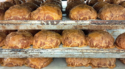 Freshly baked bread rolls stacked on trays in a bakery rack