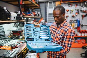 African american male buyer chooses a toolbox in a hardware store. A large selection of tools