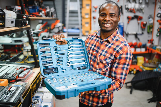African american male buyer chooses a toolbox in a hardware store. A large selection of tools