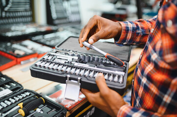 African american male buyer chooses a toolbox in a hardware store. A large selection of tools