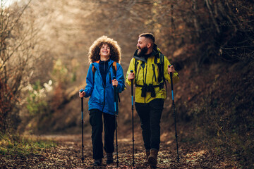 Hikers walking in forest using trekking poles and backpacks