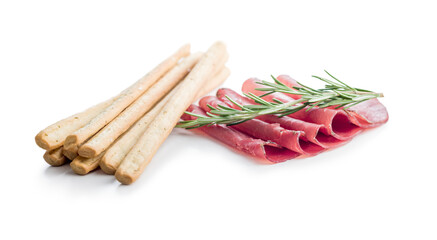 Slices of smoked bresaola and grissini sticks isolated on white background.