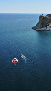 Aerial drone view of the buildings along the coastline with people parasailing in the sea in Benidorm, Spain in daylight. Vertical