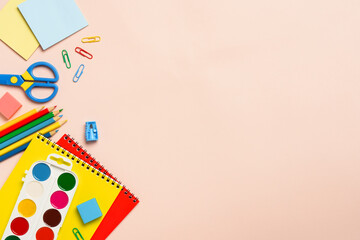 School backpack with stationery on colored background.
