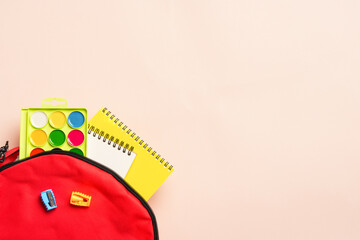 School backpack with stationery on colored background.