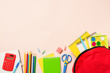 School backpack with stationery on colored background.