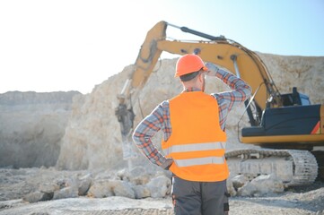 Extraction of stone. Male worker next to stone quarry. Engineer at construction site