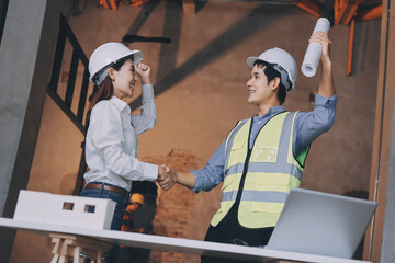Construction manager and engineer dressed in orange work vests and hard helmets explore...