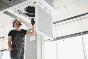 technician cleans air conditioner system in a modern apartment