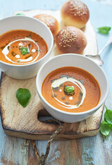 Two bowls of tomato and basil soup with homemade buns. 