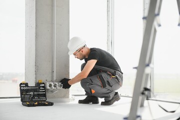 electrician installs socket boxes on the wall and puts a putty on them