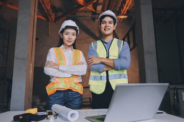 Construction manager and engineer dressed in orange work vests and hard helmets explore...