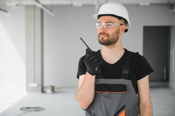 Foreman wear safety helmet and use walkie talkie to communication with team in construction site