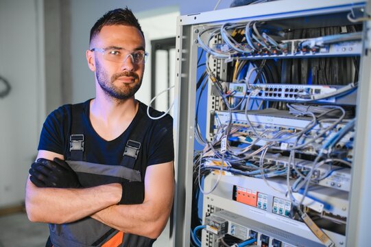 Young man is working with internet equipment and wires in server room