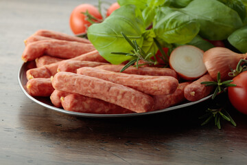 Sausages with basil and tomatoes on a old table.