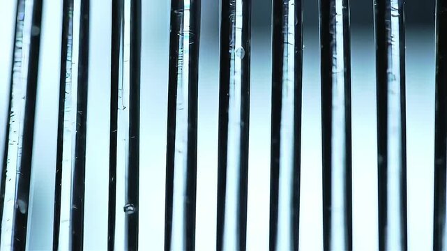 Abstract macro view of bubbling liquid inside parallel vertical glass tubes of a bioreactor.