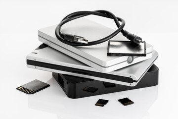 Group of external Hard disks and memory cards on white table. Data storage concept
