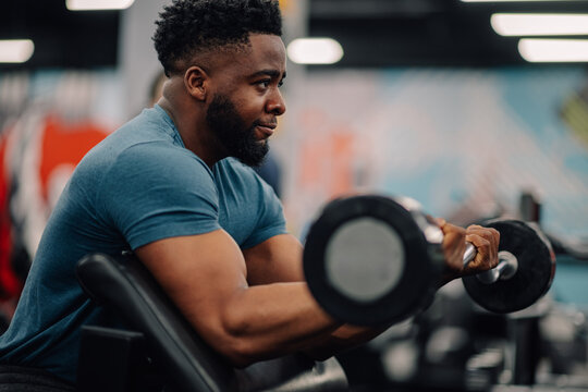 Determined bodybuilder lifting weights in modern gym for strength training
