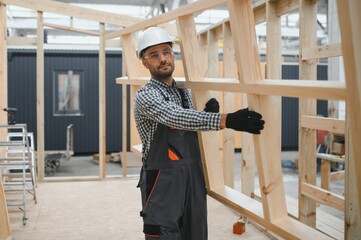 Process of construction new and modern modular house. Worker man in special protective uniform wear...