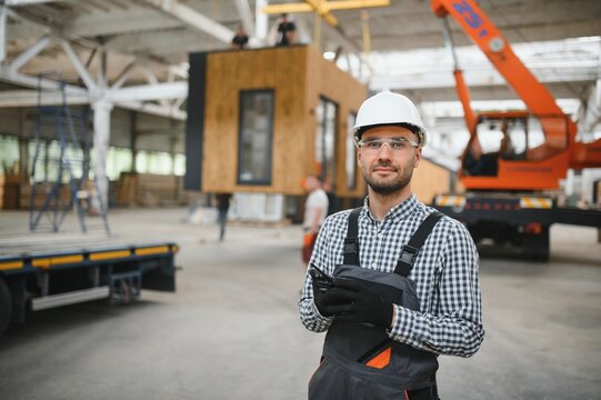 Foreman manages the loading of a prefabricated modular house to truck using walkie talkie