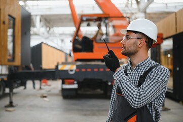 A worker controls the process of loading a modular house onto a truck. Transportation and delivery...