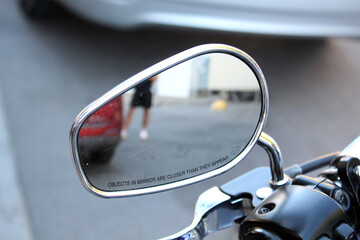 Motorcycle side mirror with chrome frame reflects blurry urban scene. Motorcycle rear view mirror....