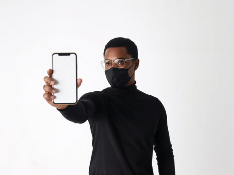 A stylish businessman in a face mask presents his phone's blank screen