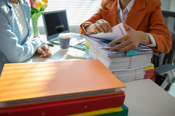 businesswoman and her secretary are helping search for documents examine large number investment...