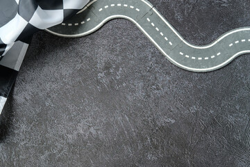 Checkered flag on winding puzzle road over dark textured background. Symbol of finish line, racing,...