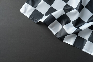 Obraz premium Checkered racing flag on dark surface, symbolizing finish line, victory, and motorsport.