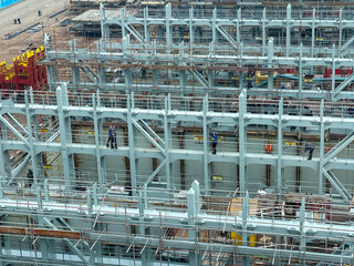 Shipyard workers wearing safety helmets and uniforms working on the structure of a large vessel...