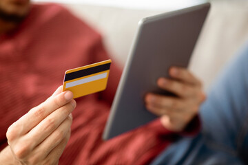 Closeup of male hands with modern digital tablet and credit card. Unrecognizable man shopping online or making order while staying home, using pad, closeup. E-commerce concept