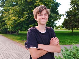 Portrait of a happy teenage boy in a public park. A kind teenage boy smiles and looks into the camera.