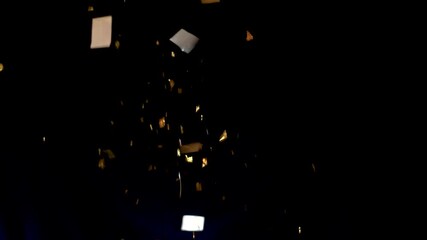 Golden confetti and sparkling glitter gracefully fall against a deep black background, creating a festive, luxurious, and celebratory atmosphere