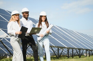 Male and female engineers worker working in solar panels power farm. technician working at solar...