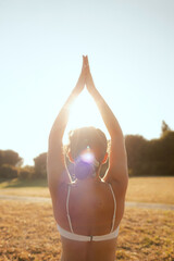 Young woman in sportswear stretching body on fitness mat at public park, doing yoga. Healthy...