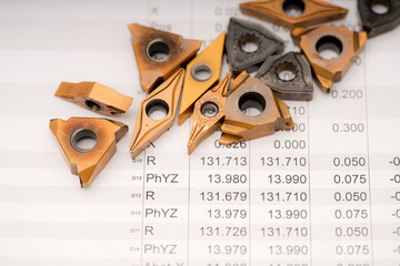 Metal cutting tools and technical specifications displayed on a workbench with detailed...
