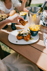 A person is eating a sandwich and dipping fries into a bowl of sauce