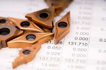 Metal cutting tools arranged on a sheet of numerical data showcasing precision measurements and...