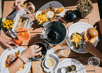 A table with a variety of food and drinks, including a bowl of fries, a sandwich