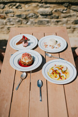 A table with four plates of food, including a dessert with strawberries on top