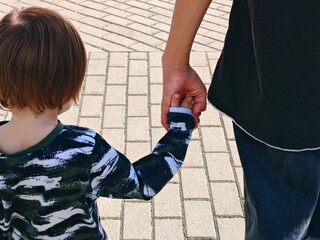 An adult holds a child's hand by the hand. Family concept. Childhood, parenting. Two brothers.