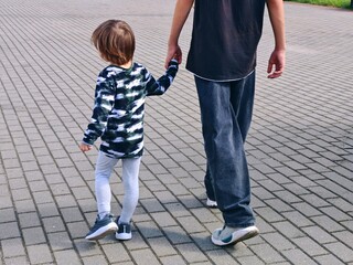 An adult holds a child's hand by the hand. Family concept. Childhood, parenting. Two brothers.