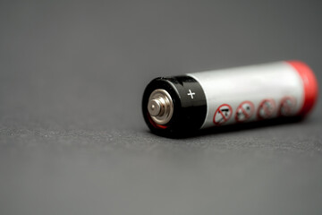 Close-up view of a battery showing positive and negative terminals on a dark surface