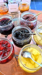 Glass jars filled with colorful jams and fresh fruit salad presenting appealing breakfast spread at...