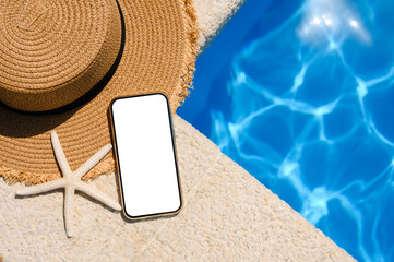 Smartphone with white display near the pool. Hat, starfish and phone with white display. Top view