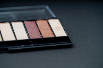 Makeup palette with various eyeshadow shades on a dark background for beauty enthusiasts